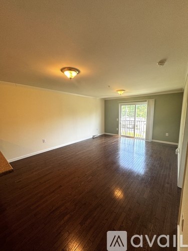 A room with wooden floors and a window with blinds.