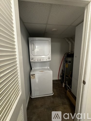 A white dishwasher is in a small, empty room.