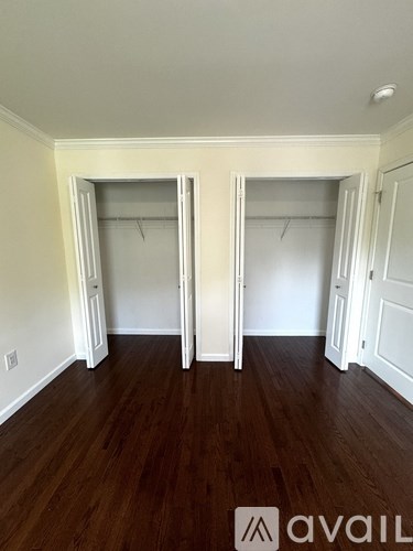 A room with wood floors and three open closets.