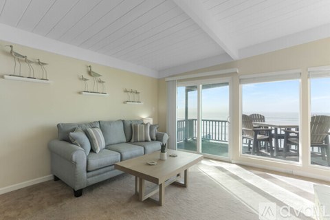 A living room with a grey couch and a glass door leading to a balcony.