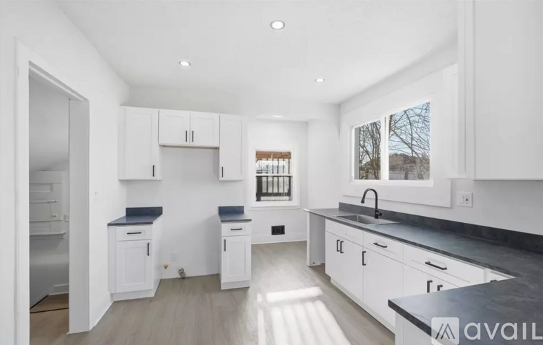 A modern kitchen with white cabinets and a black countertop.