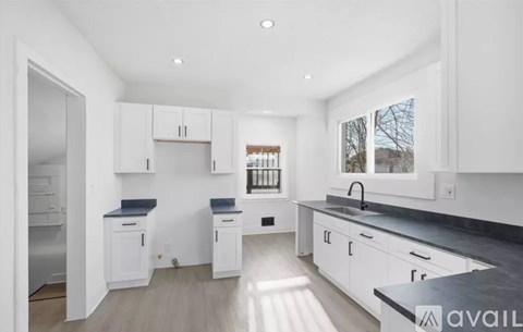 A modern kitchen with white cabinets and a black countertop.