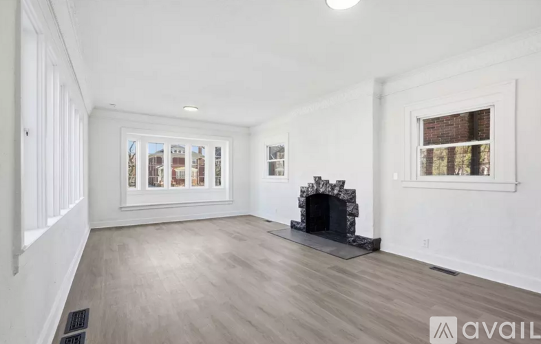A spacious living room with a fireplace and a view of the city through the windows.