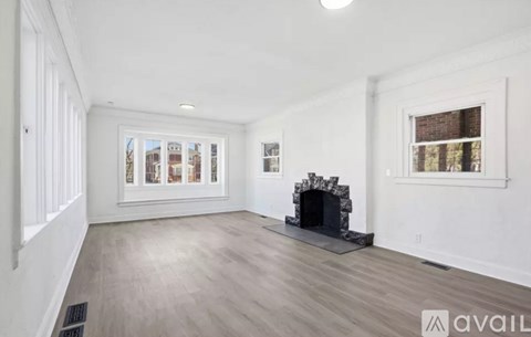 A spacious living room with a fireplace and a view of the city through the windows.