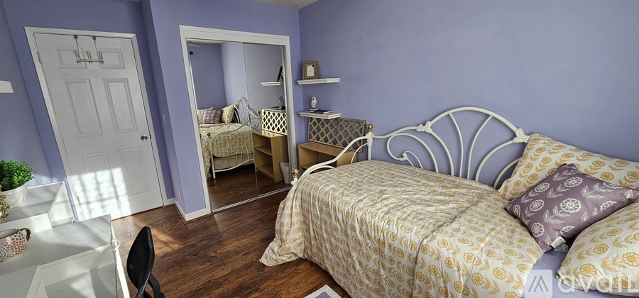 A bedroom with a bed, a desk, and a mirror.
