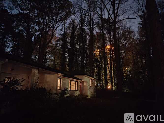 A house is lit up at night with trees in the background.