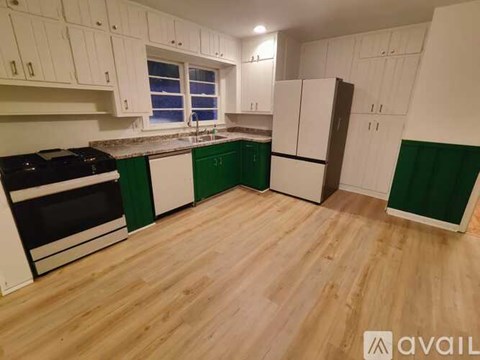 A kitchen with white cabinets and green backsplash.