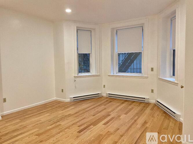 A room with wooden flooring and two windows.