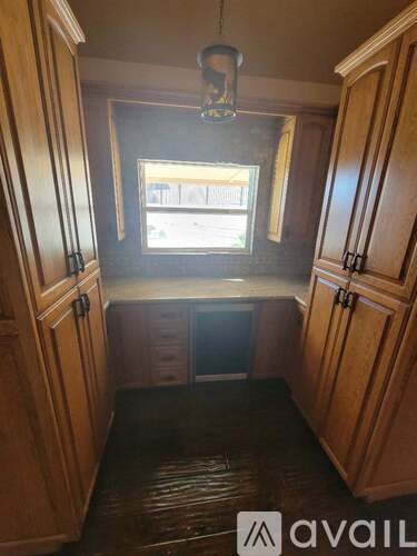 A small kitchen with wooden cabinets and a window.