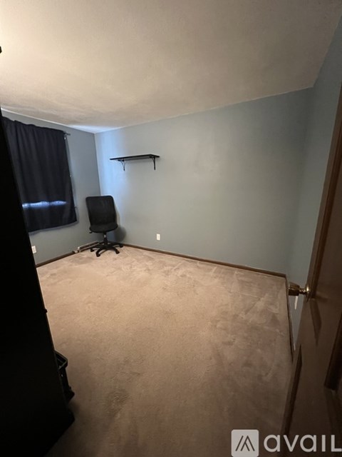 A room with a black chair and a black curtain.