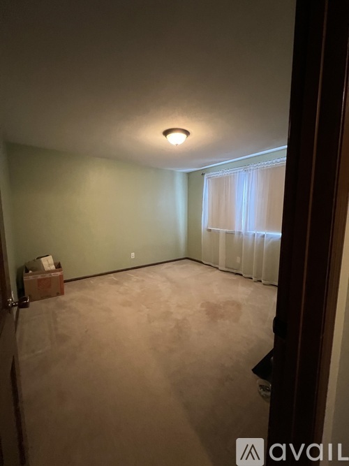 A room with a window covered by white curtains and a ceiling light.
