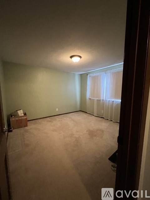 A room with a window covered by white curtains and a ceiling light.