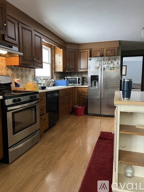 A kitchen with wooden cabinets and a stainless steel refrigerator.