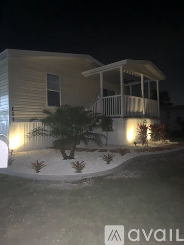 A house with a lit up porch and a tree in front.