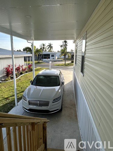 A white car is parked on a concrete driveway.