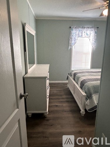 A small bedroom with a bed, dresser, and window.
