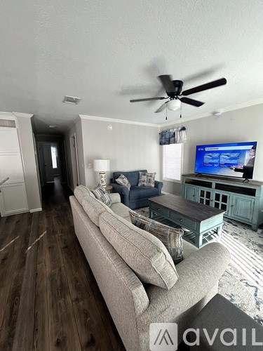 A living room with a couch, a television, and a ceiling fan.