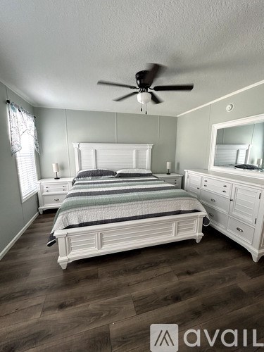 A bedroom with a bed, dresser, and mirror.