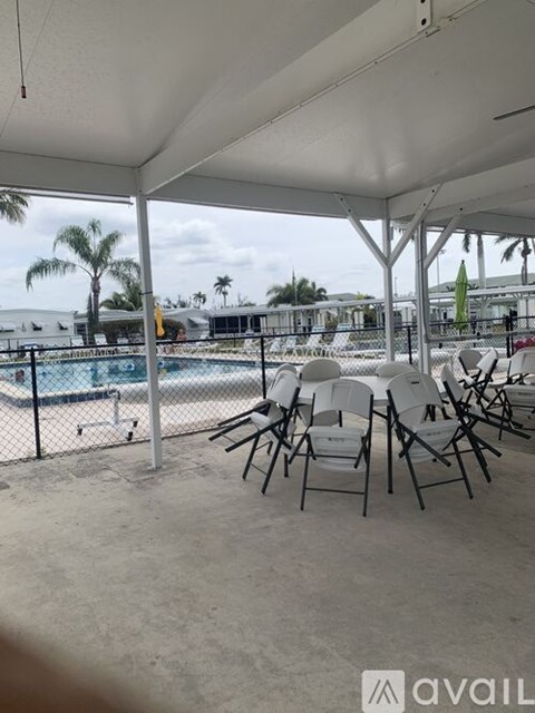 A white tent with chairs and a pool in the background.