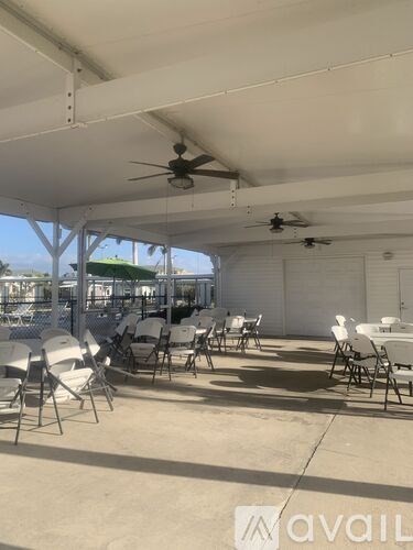 A patio with white chairs and a ceiling fan.