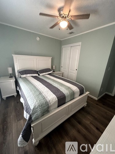 A bedroom with a bed, nightstand, and ceiling fan.