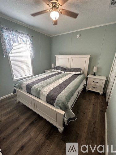 A bedroom with a bed, nightstand, and window.