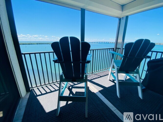 Two chairs are on a balcony overlooking a body of water.