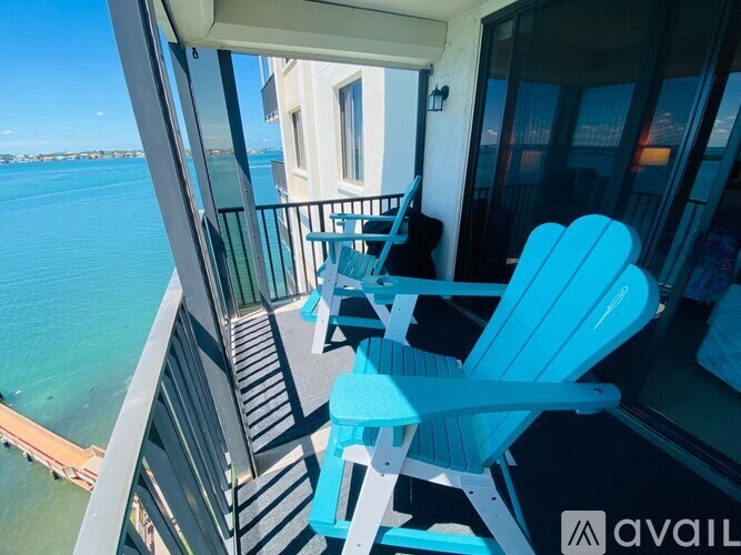 Two blue chairs on a balcony overlooking the water.