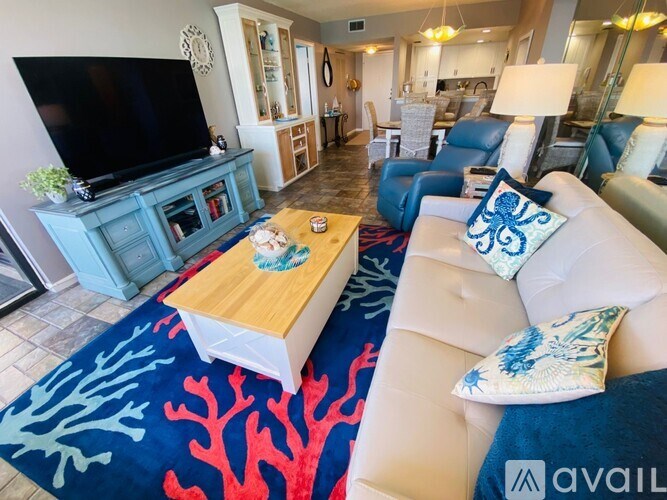 A living room with a white couch and a blue rug.