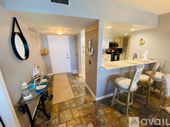 A hallway with a table and chairs leading to a kitchen.