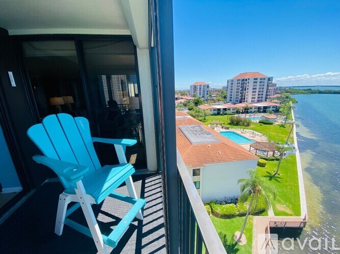 A blue chair is on a balcony overlooking a body of water.