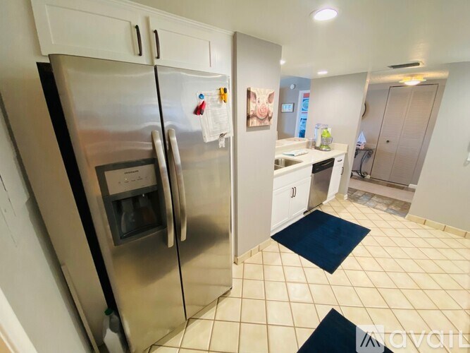 A kitchen with a stainless steel refrigerator and white cabinets.