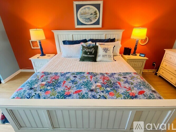 A bedroom with a floral bedspread and two pillows with the word "Family" on them.