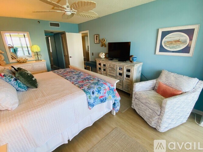 A bedroom with a bed, chair, and a ceiling fan.
