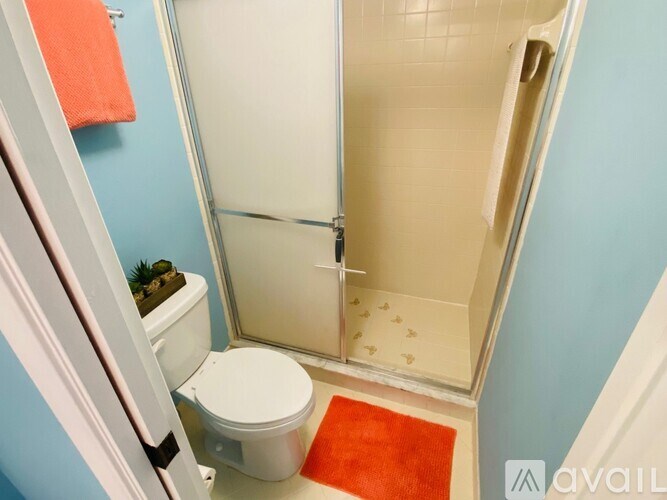 A bathroom with a toilet, a shower, and a red towel.