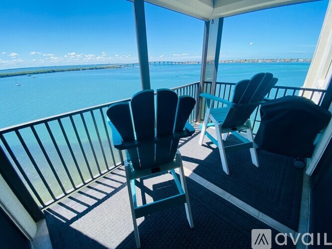 Two chairs are on a balcony overlooking a body of water.