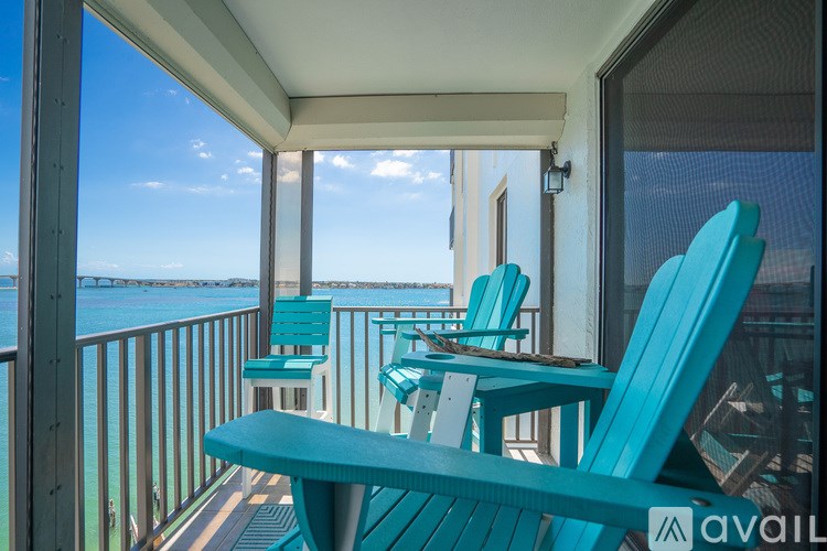 A wooden deck overlooks a body of water with a bridge in the distance.