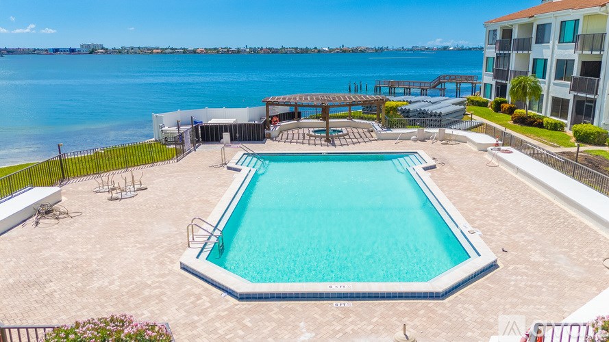 A large swimming pool with a deck and a view of the water.
