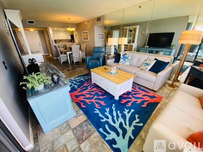 A living room with a white couch and a blue rug.
