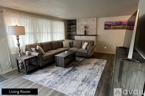 A living room with a grey sofa, a table with a lamp and a painting on the wall.