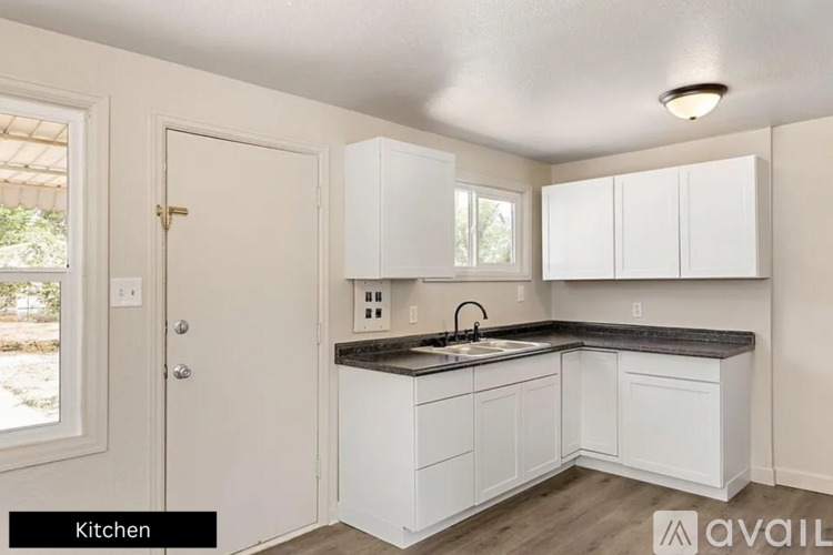 A kitchen with white cabinets and a black countertop.