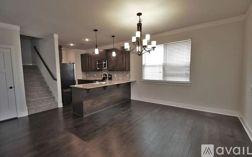 A modern kitchen with a wooden island and a chandelier.
