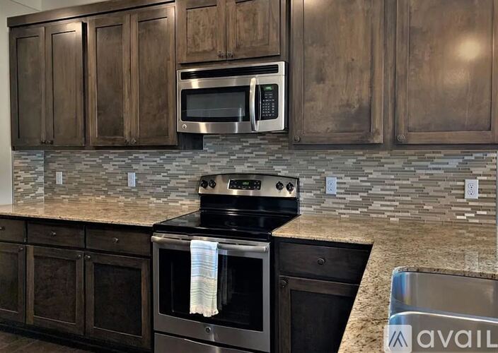 A kitchen with dark wood cabinets and a black stove top oven.