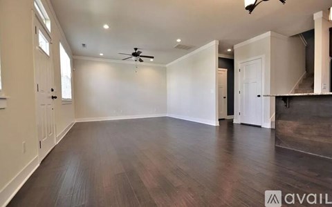A spacious room with a ceiling fan and hardwood flooring.