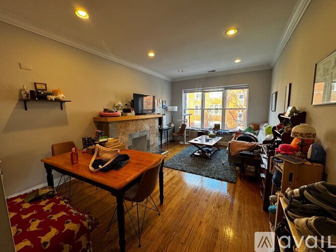 A living room with a wooden table and chairs, a fireplace, and a rug on the floor.