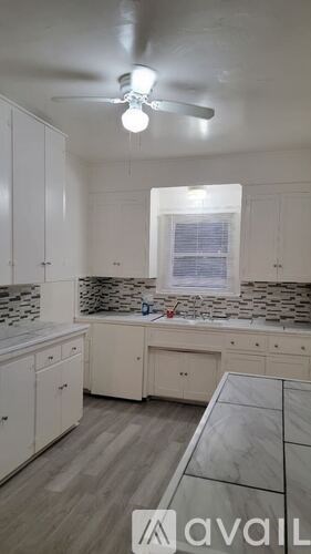 A kitchen with white cabinets and a fan on the ceiling.
