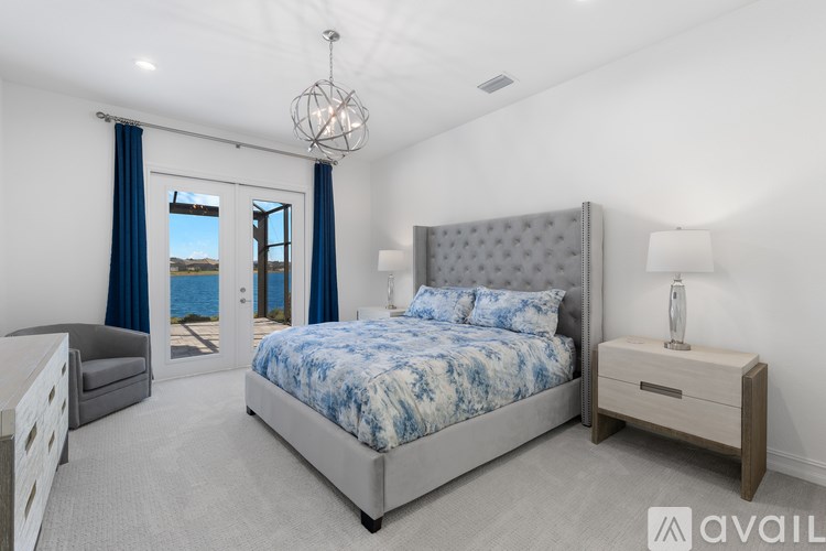 A bedroom with a large bed, a nightstand, and a window with blue curtains.