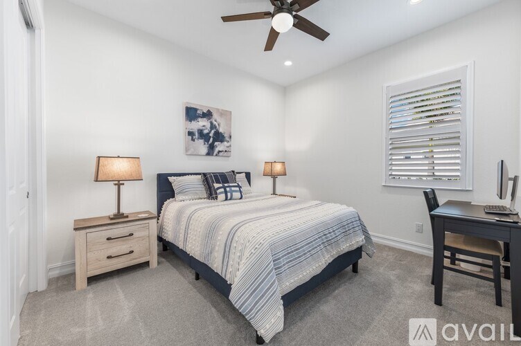 A bedroom with a bed, desk, and chair.