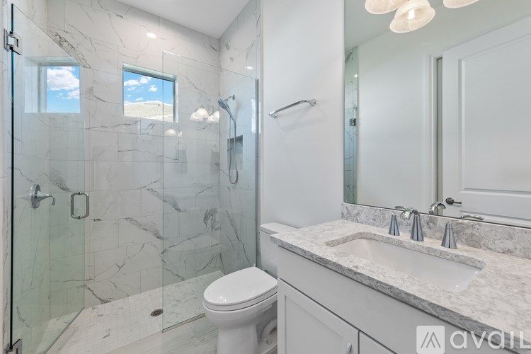 A bathroom with a marble countertop and a glass shower stall.