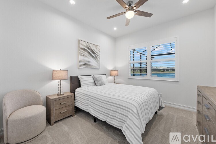 A bedroom with a bed, chair, and ceiling fan.
